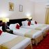 Safeer almisk Hotel in Mecca guest room with three single beds, desk, curtains and wall art