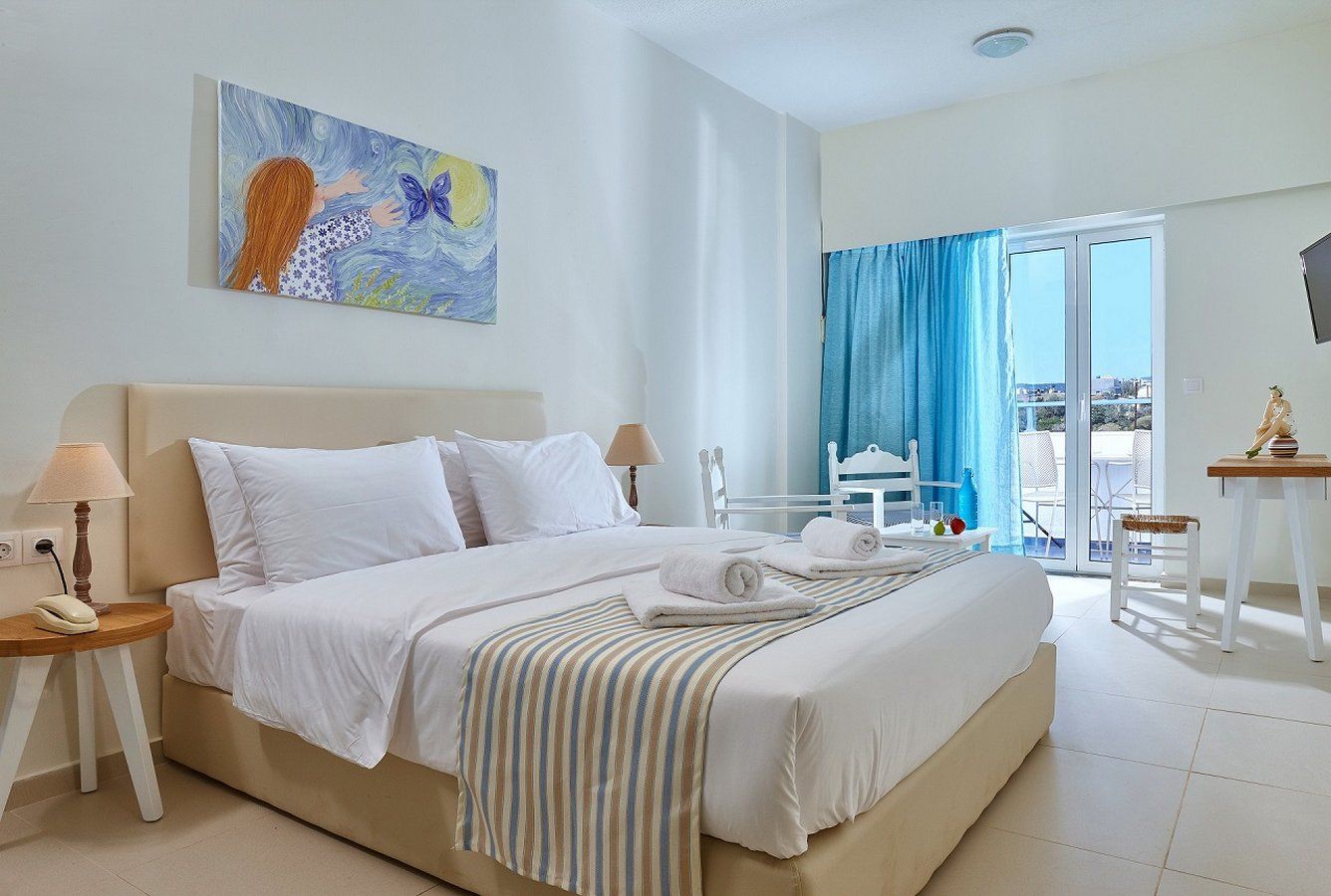 Vasia Ormos Hotel room in Agios Nikolaos with king bed, balcony doors, and bright sea-facing light