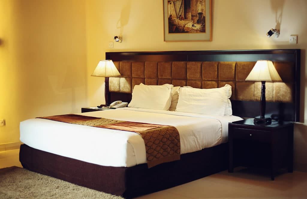 The Avenue Hotel & Suites in Chittagong guest room with king bed, bedside lamps, and framed wall art