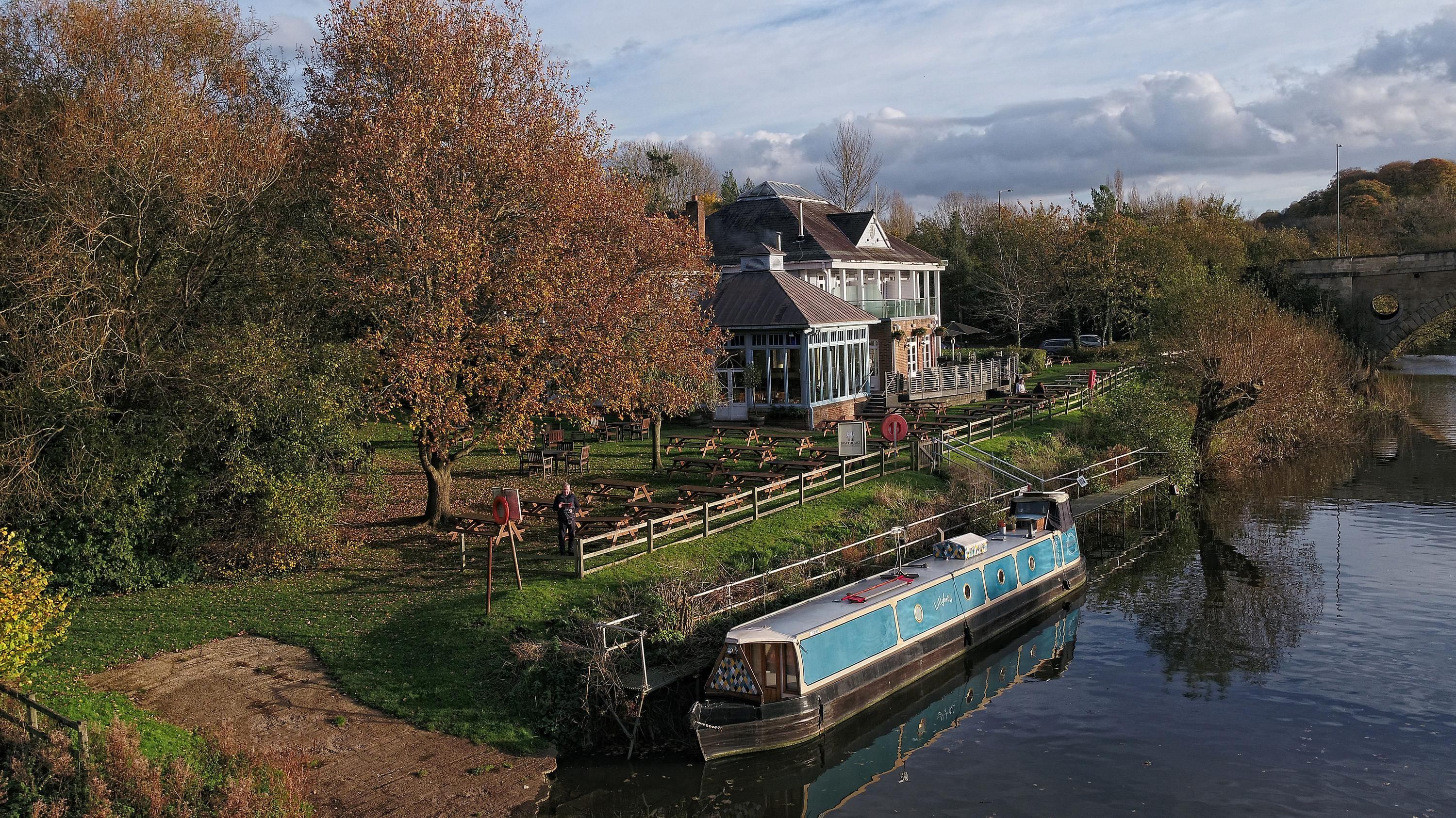 The Boathouse in Bath beside the canal with a narrowboat, trees, and riverside terrace