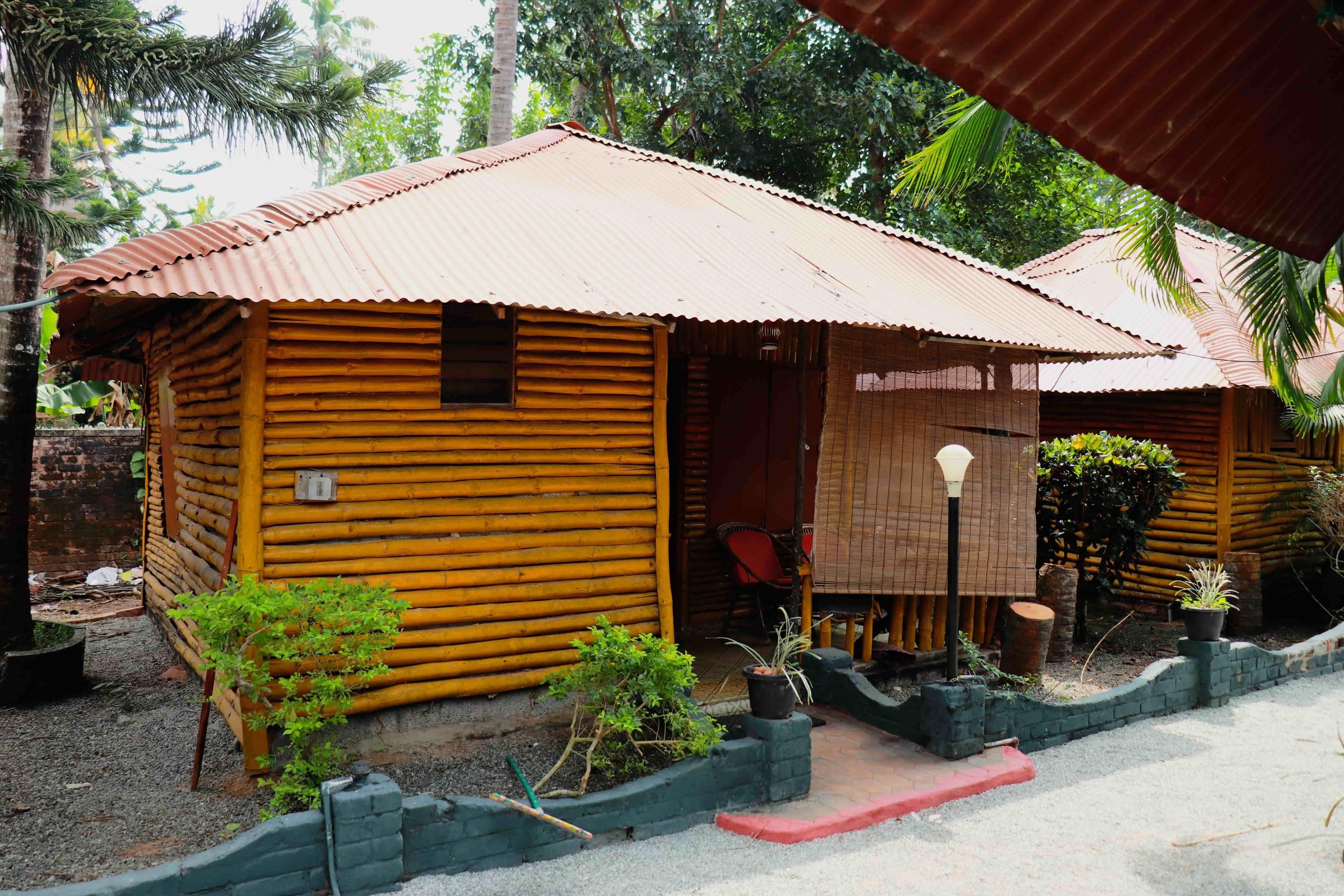 Kerala Bamboo House in Varkala: bamboo cottage with corrugated roof, shaded porch, and tropical greenery