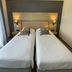 Hôtel Le Mas del Pechs in Sarlat-la-Canéda guest room with two twin beds and wall sconces