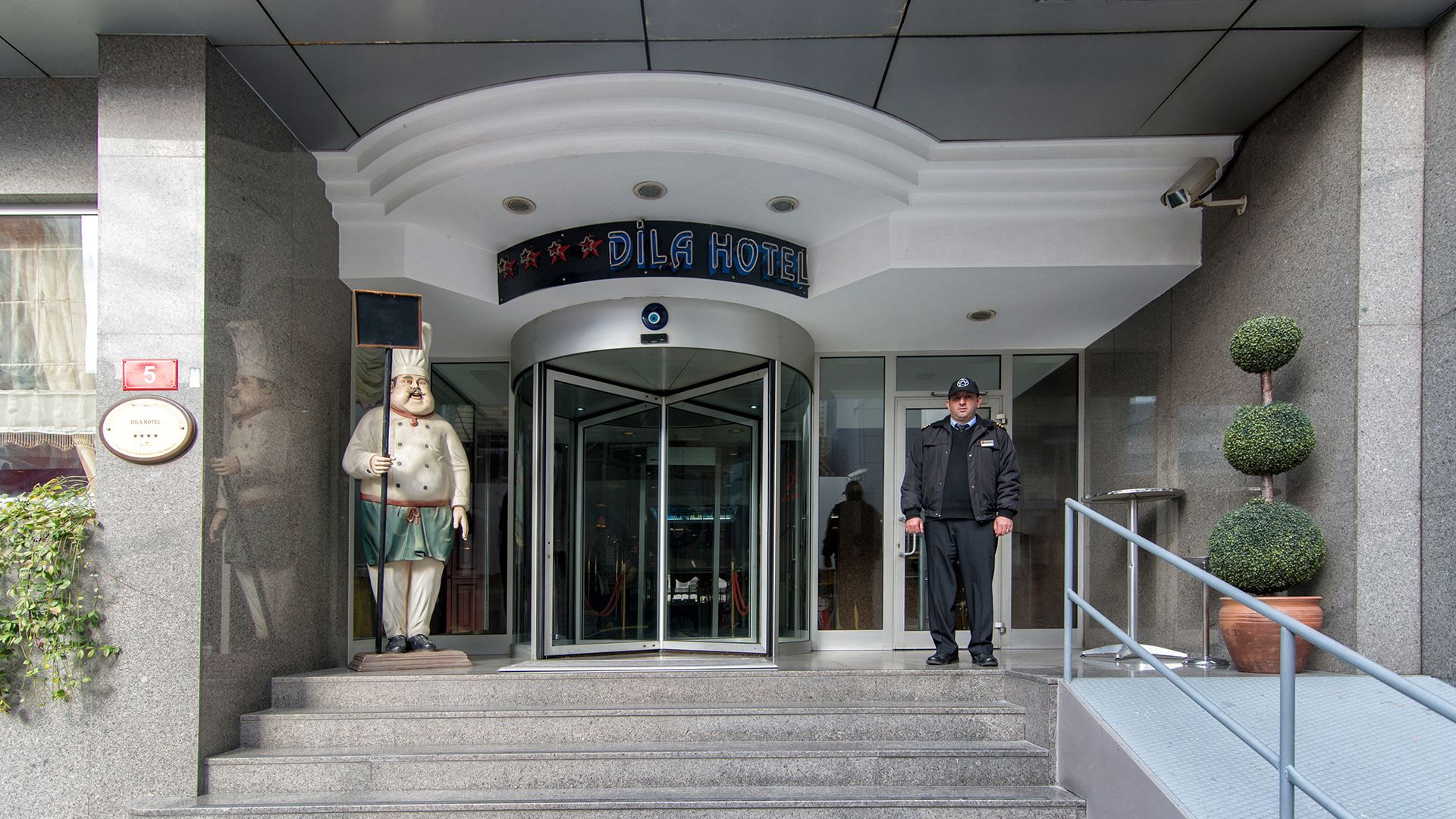 Entrance of Dila Hotel in Istanbul with revolving glass doors and two guards at the steps