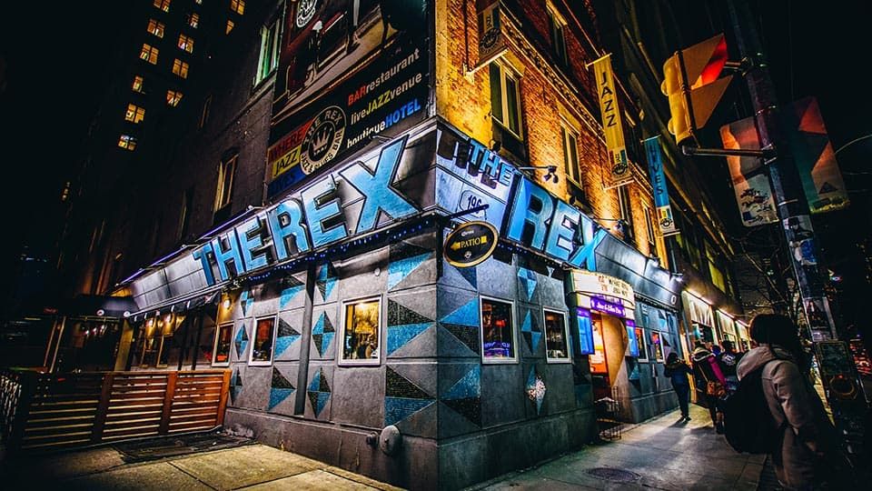 The Rex Hotel Jazz & Blues Bar in Toronto at night, with a bright corner sign and street view