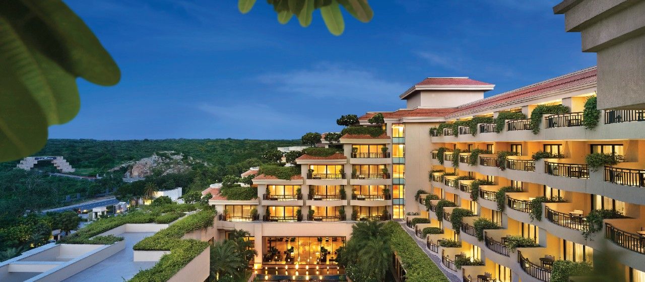 Taj Surajkund Resort & Spa, Delhi Ncr in Faridabad with hillside view and illuminated balconies at dusk
