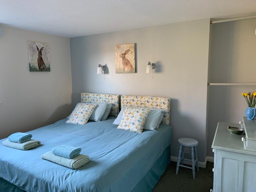 Bratton View in Barnstaple: bright bedroom with twin bed, blue bedding, wall art and bedside stool