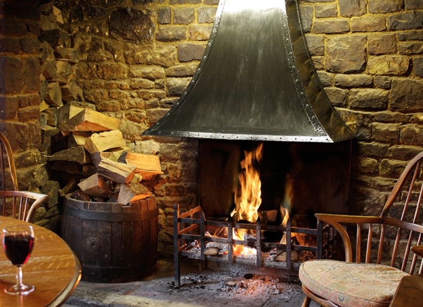 The Anchor Inn Bristol stone fireplace with burning fire, stacked logs, and cozy seating
