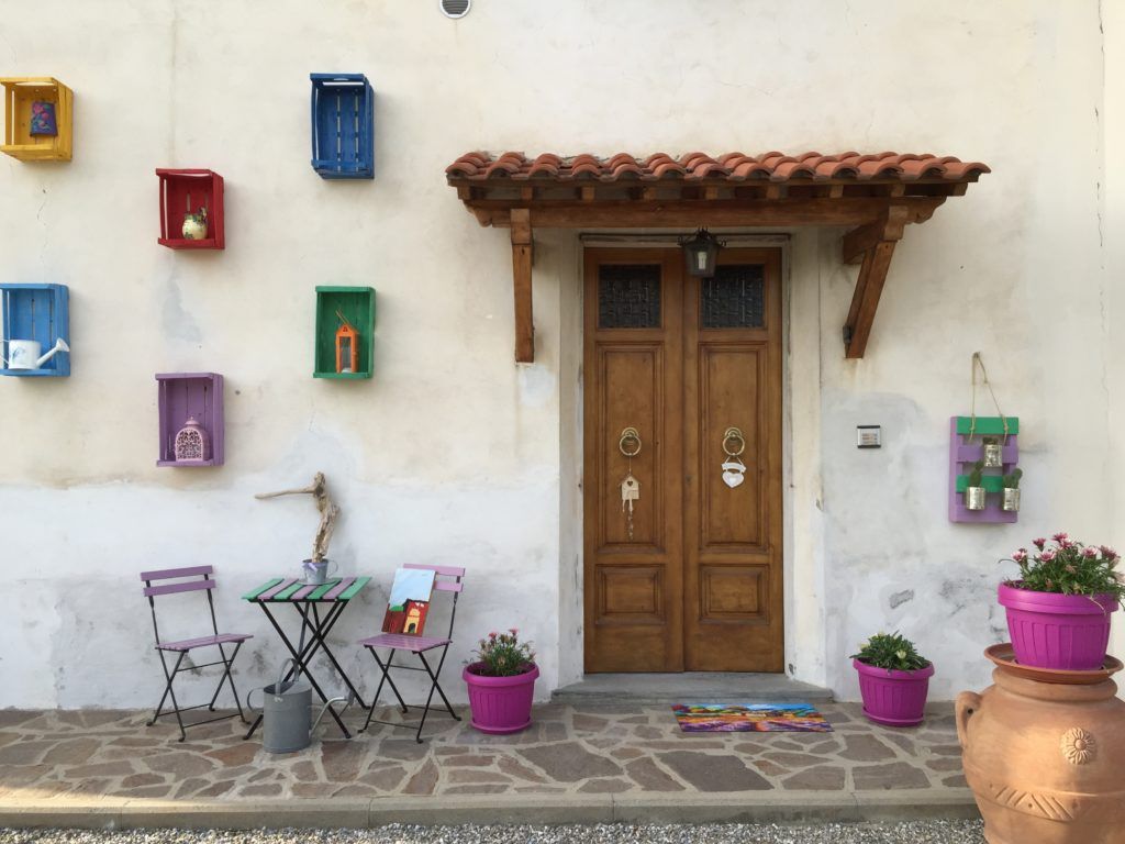 B&B Mangiafuoco in San Miniato, colorful wall shelves and a wooden door with potted flowers outside