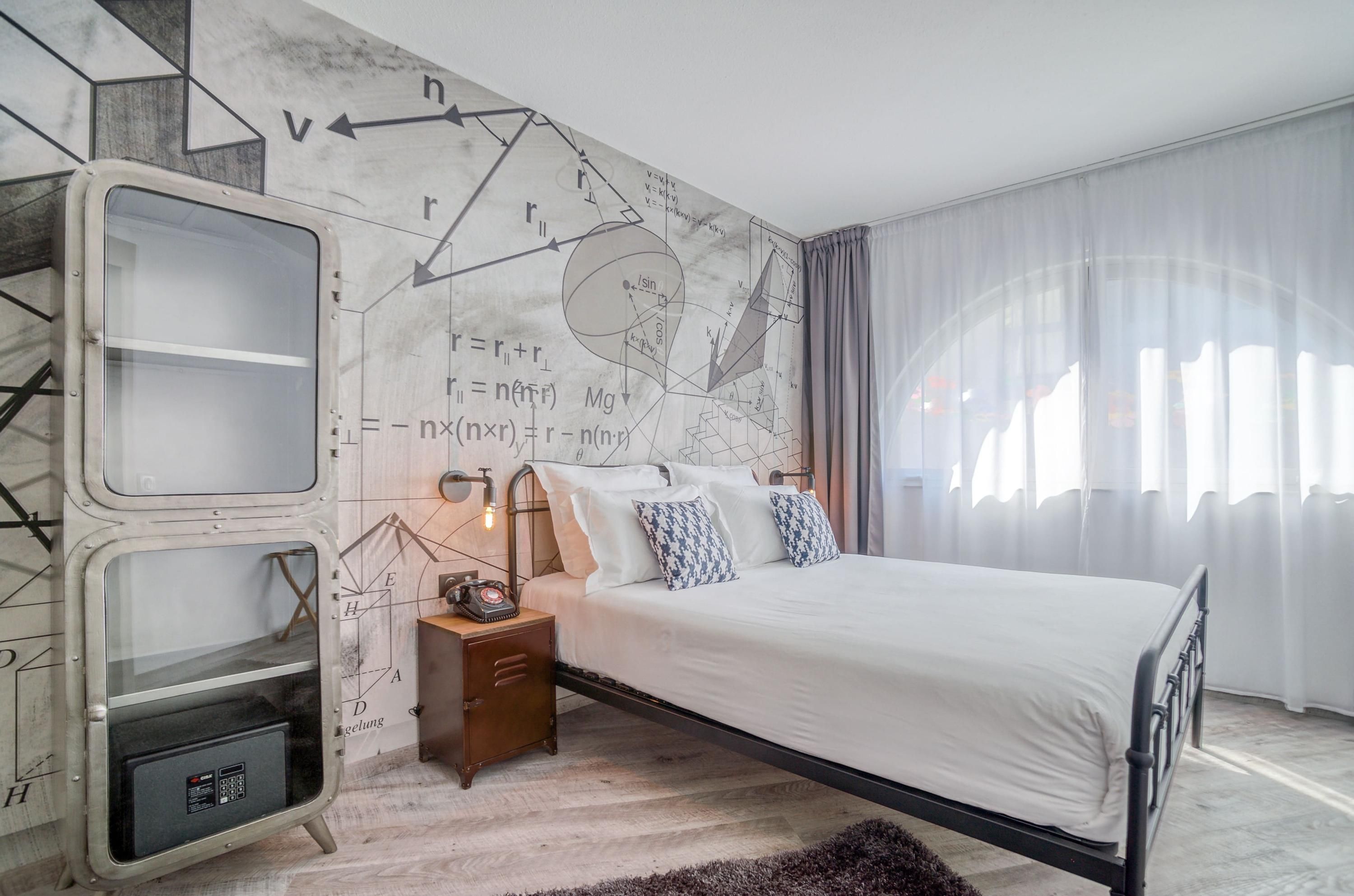 La Maison Hotel Mulhouse in Mulhouse: bright guest room with double bed, mural wall art, and large sheer curtains