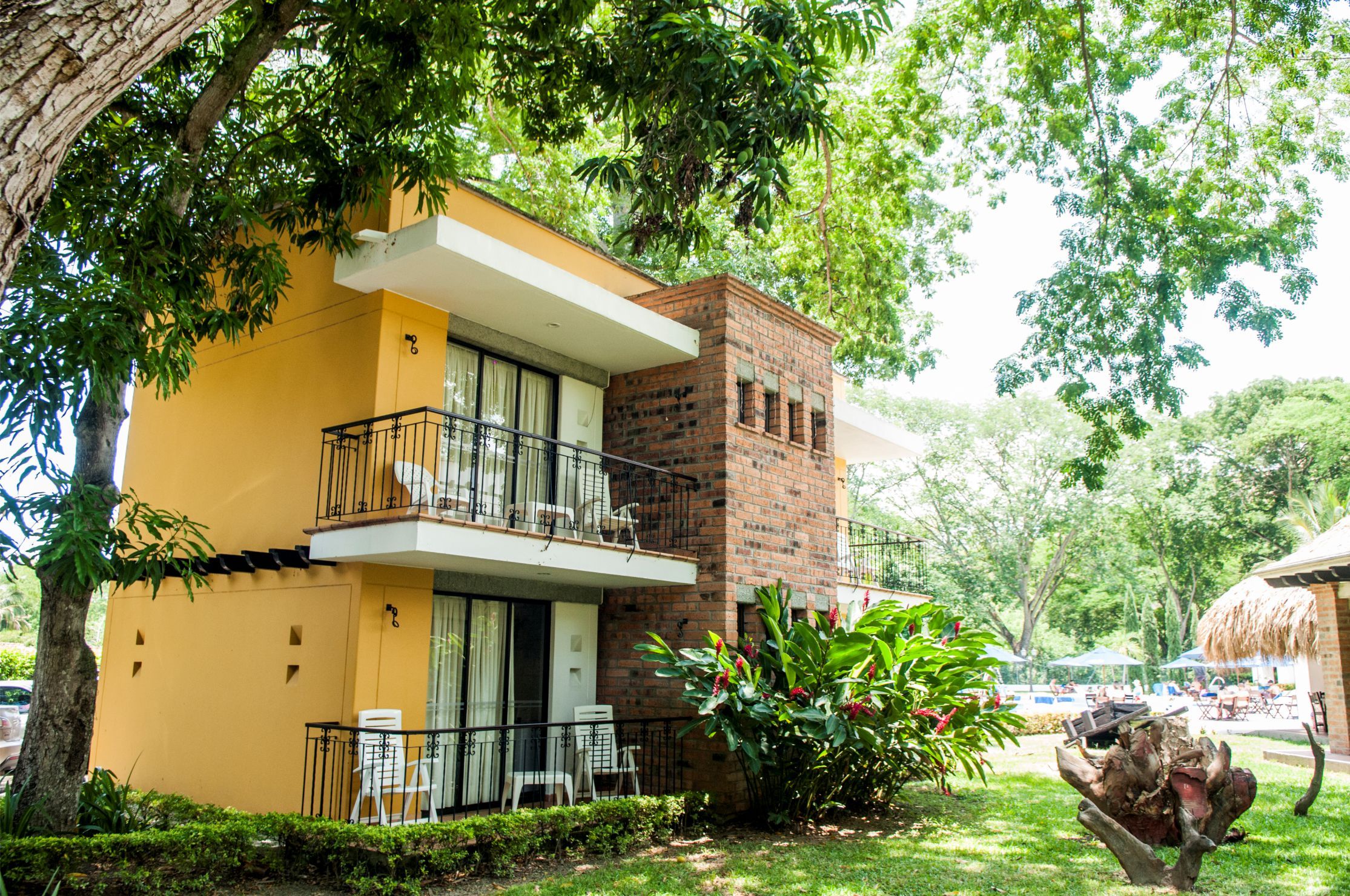 Hotel Villa Del Marques in Sopetrán with a two-story yellow building, balconies, and lush tropical trees