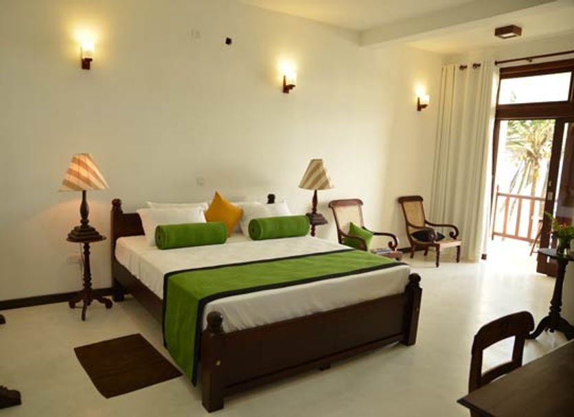 Surf Station, Ahangama guest room with king bed, wall sconces, chairs and balcony doors