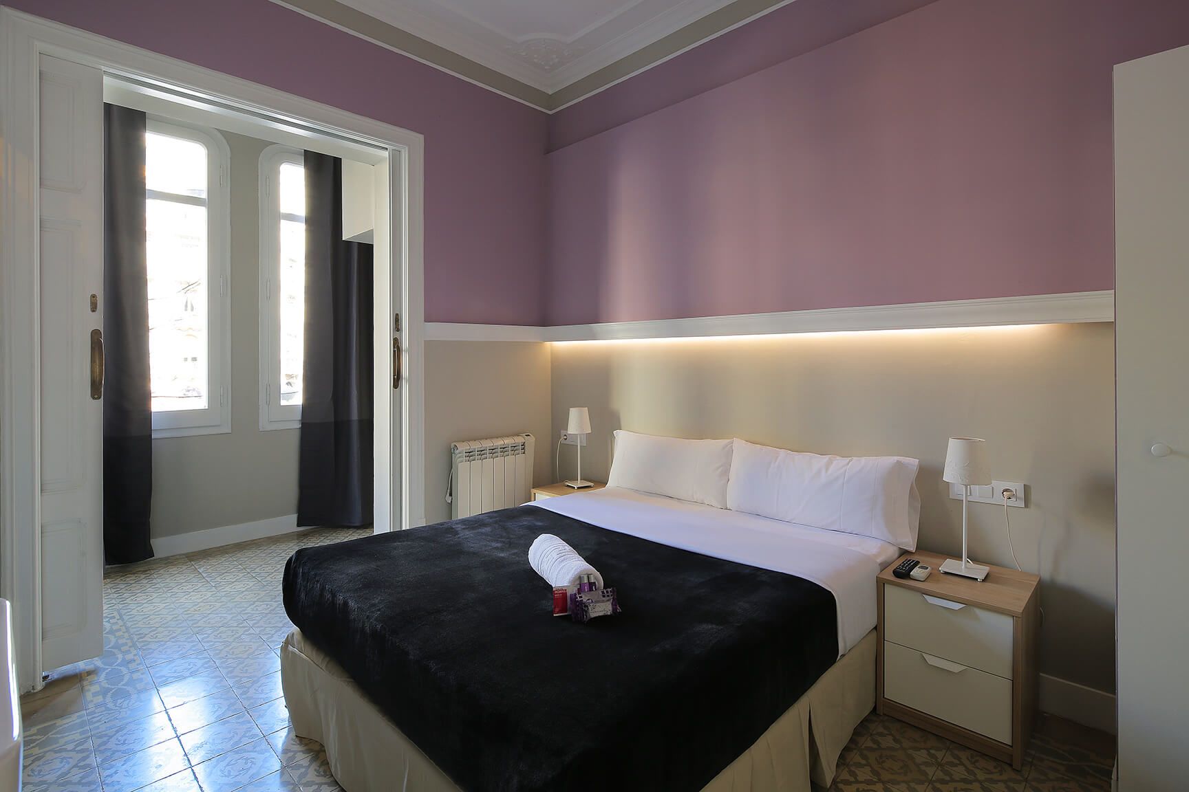 Hostal Que Tal room in Barcelona with double bed, purple walls and balcony doors with curtains