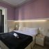 Hostal Que Tal room in Barcelona with double bed, purple walls and balcony doors with curtains