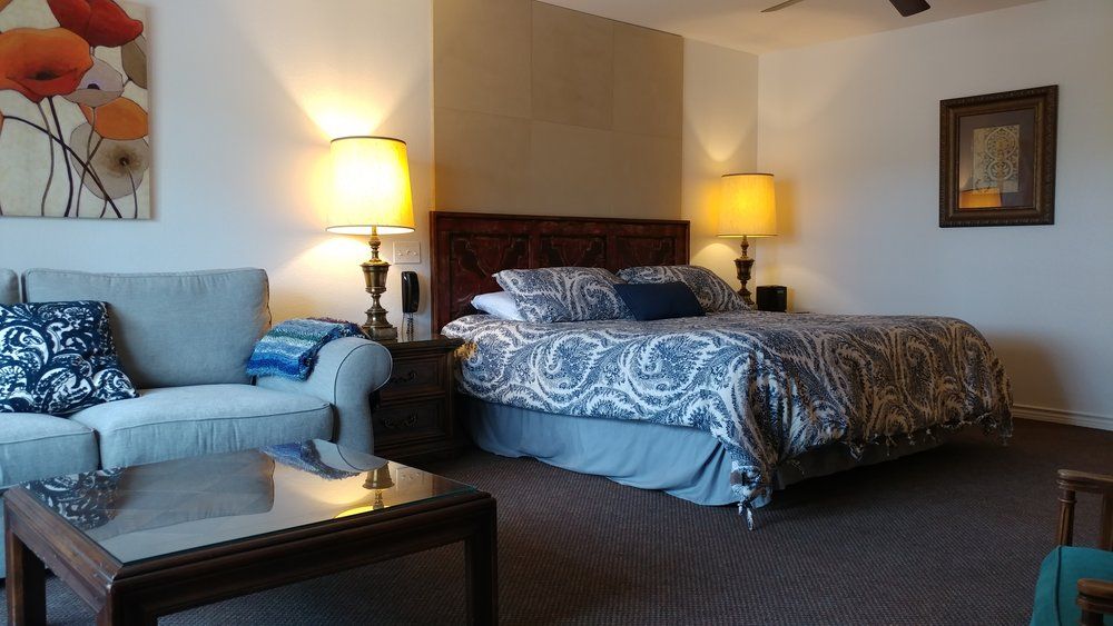 Wimberley Inn in Wimberley guest room with king bed, sofa, lamps, and wall art