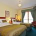 Anchor Guesthouse Dublin twin room with two beds, bedside lamps, and window with green curtains