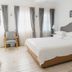 Vintage Alacati guest room in Alacati with a bed, armchair, and tall sheer-curtained windows