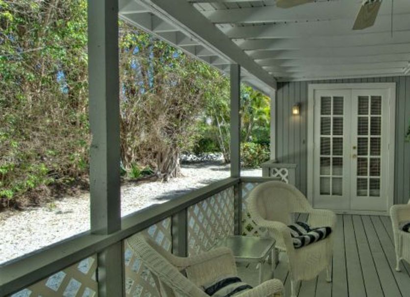 Seahorse Cottages on Sanibel - Adults Only porch with wicker chairs and forested walkway in Sanibel