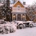 Vardshuset Idyllen in Söråker, snow-covered yellow house with balcony and rustic wagon in front