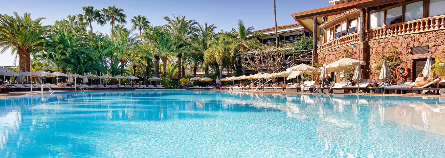 Hotel Parque Tropical in Maspalomas with a large outdoor pool and palm trees beside sun loungers