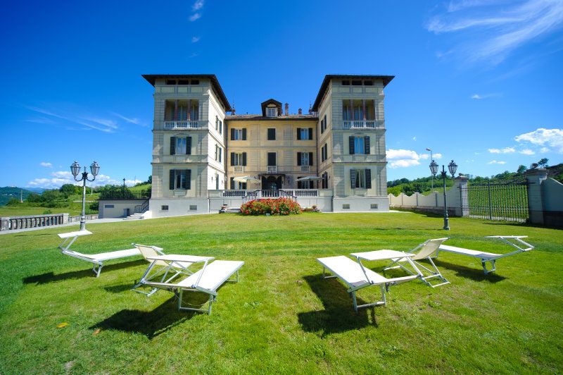 Hotel Villa La Bollina in Serravalle Scrivia with a grand villa façade and lounge chairs on a lawn