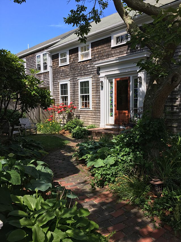 The Chestnut House in Nantucket with a brick garden path leading to a shingled house entrance