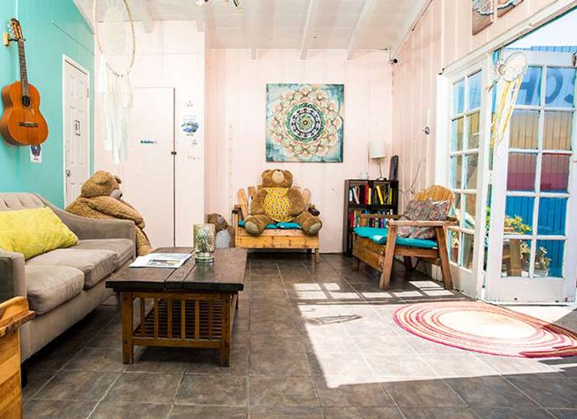 Ith San Diego Beach Bungalow Surf Hostel lounge with guitars, sofa, and bright patio doors in San Diego