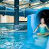 Primavera Jastrzebia Gora indoor pool with child sliding through a blue waterslide in Jastrzębia Góra
