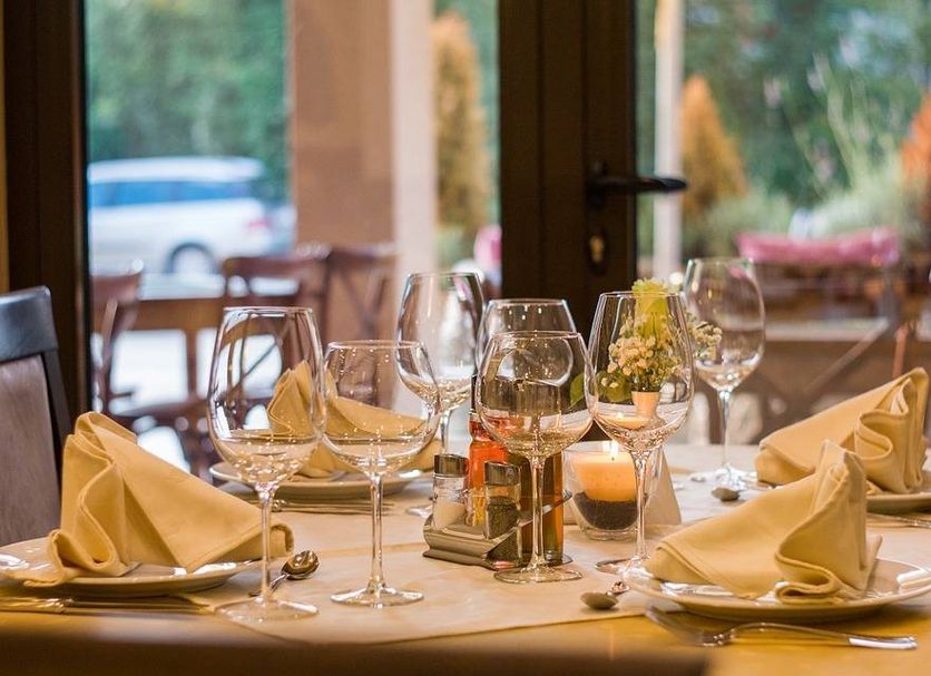 Hôtel le Relais dining table set with wine glasses, folded napkins, candle and flowers in Biscarrosse