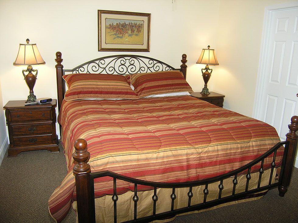 Black Forest Bed & Breakfast in Helen: cozy guest room with wrought-iron bed, striped bedding, and bedside lamps