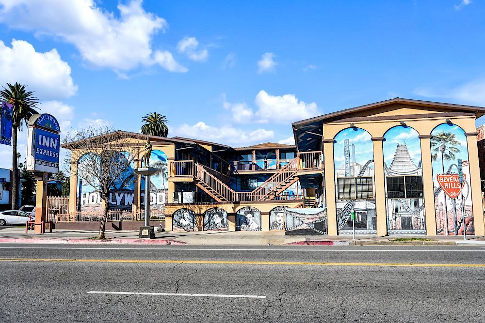 Hollywood Inn Express North in Los Angeles exterior with mural, palm trees, and arched windows