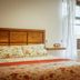 Casa Rural Arona guest room with floral bedspread, window, sheer curtains and wooden chair in Arona