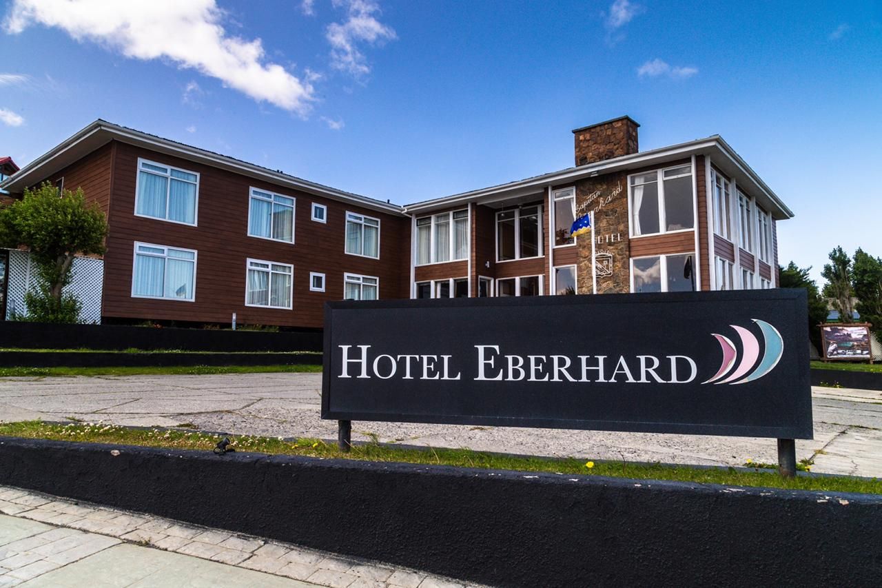 Hotel Capitan Eberhard in Puerto Natales with a roadside sign and brick hotel building under blue sky