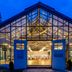 Hotel Döllnsee-Schorfheide in Templin with a glass-fronted pavilion and open double doors at dusk