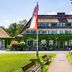 Hotel Döllnsee-Schorfheide in Templin with ivy-covered facade, manicured lawn and flag-lined walkway