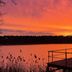 Hotel Döllnsee-Schorfheide in Templin with sunset over lake and a wooden deck with railing