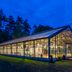 Hotel Döllnsee-Schorfheide in Templin, glass-walled pavilion glowing at dusk beside trees