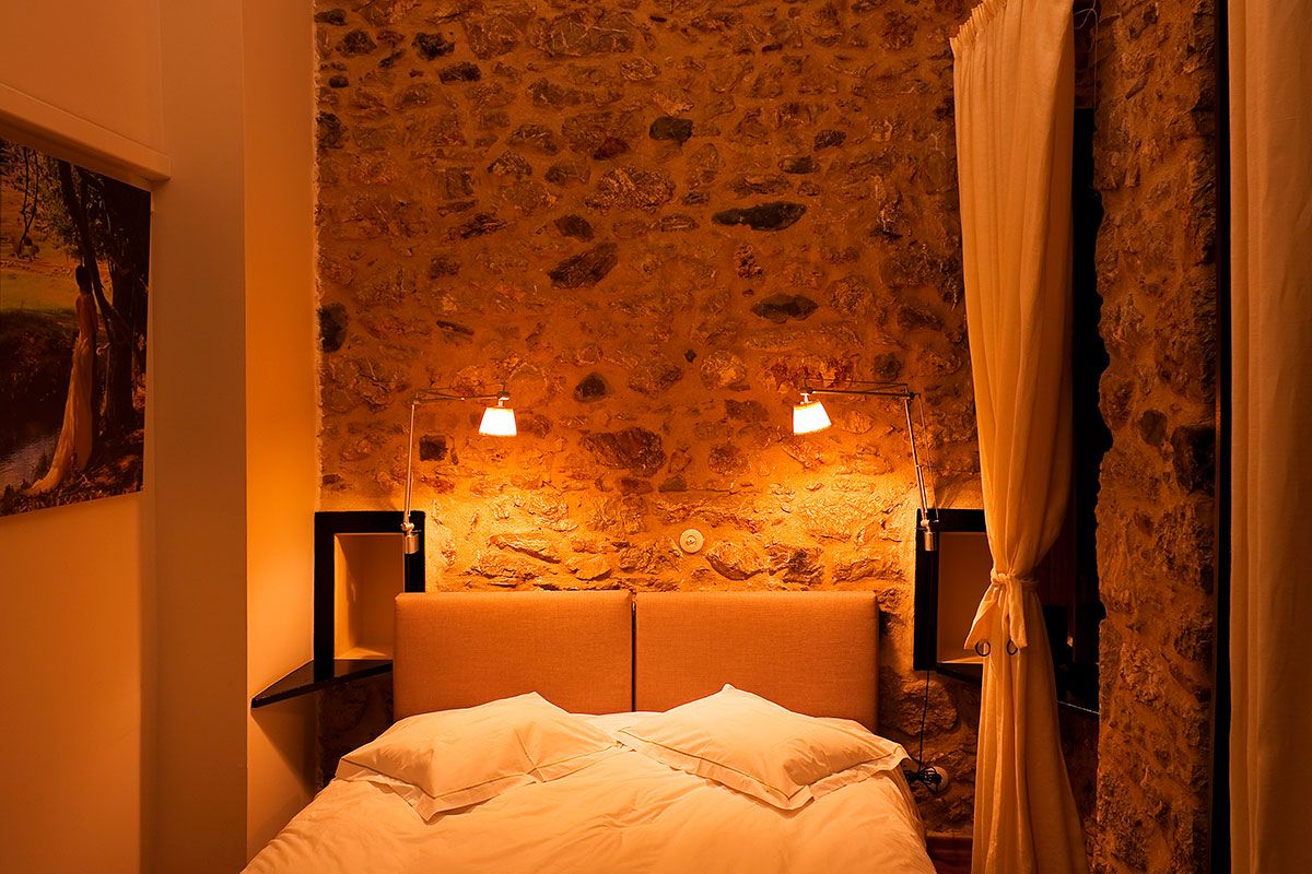 Guesthouse Theonimfi in Dimitsana: cozy stone-walled bedroom with warm bedside lighting and canopy curtain