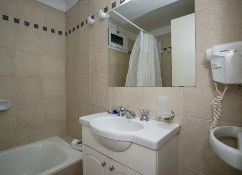 Villa Gesell Spa & Resort bathroom with bathtub, sink, mirror, and wall-mounted hair dryer in Villa Gesell