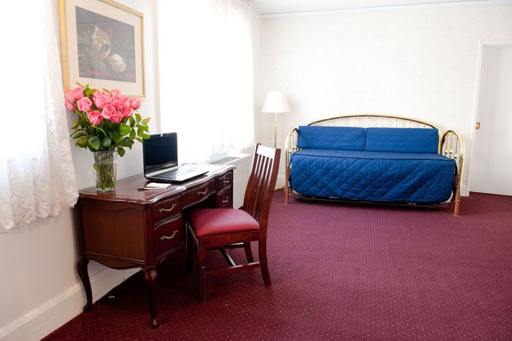 Windsor Park hotel room in Washington, D.C. with desk, chair, blue sofa bed and floor lamp