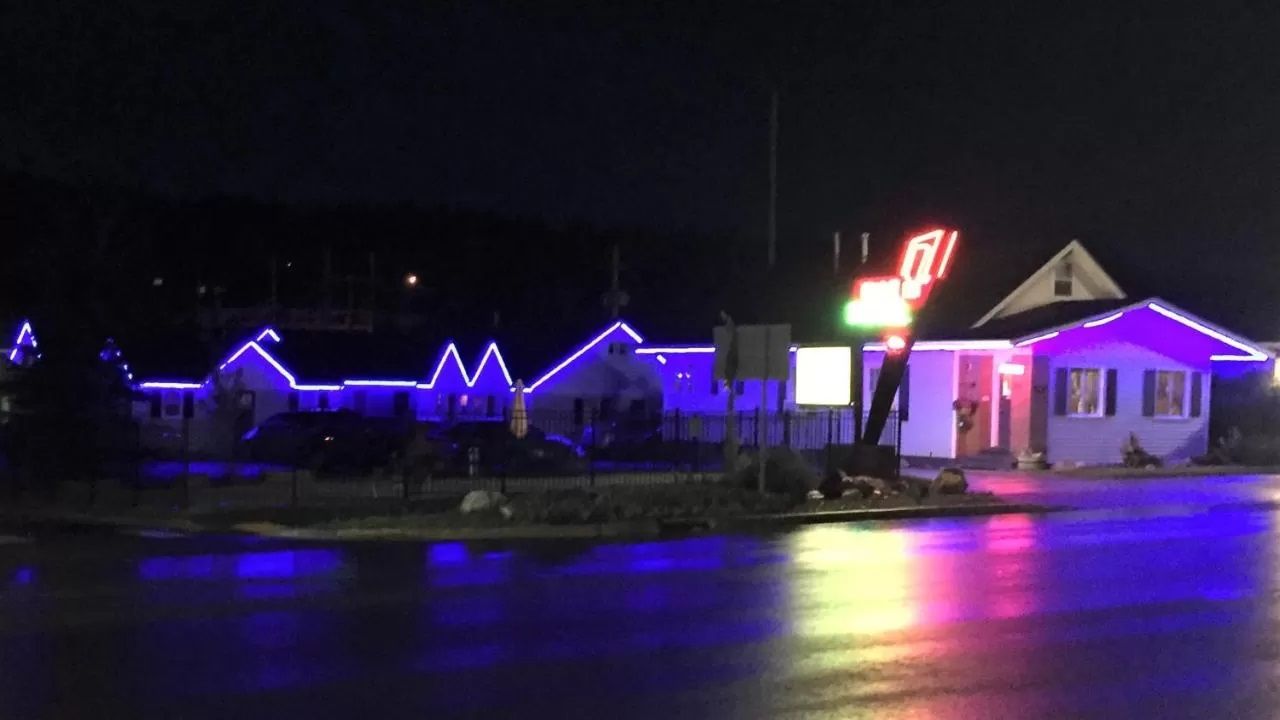 Black Hills Mile Hi Motel in Custer at night with purple-lit roofline and wet road reflections