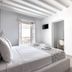 Mykonos Essence Adults Only bedroom with white linens, exposed beams, and balcony doors in Mykonos