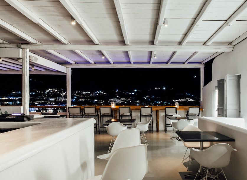 Mykonos Essence Adults Only in Mykonos terrace with seating and city lights at night