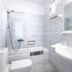 Mykonos Essence Adults Only bathroom with bathtub, shower, wall-mounted sink and large mirror in Mykonos