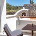 Mykonos Essence Adults Only balcony with table, lounge chairs and stone wall view in Mykonos
