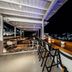 Mykonos Essence Adults Only rooftop bar with wooden counter, stools and night views over Mykonos