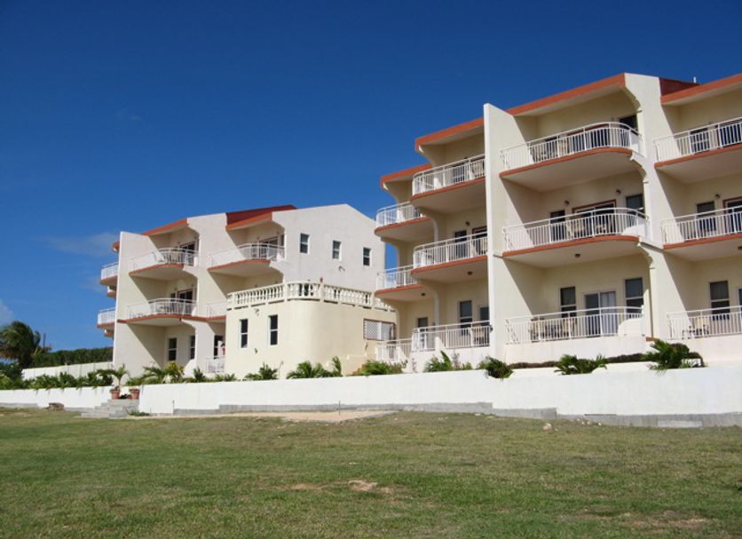 Ocean Terrace Condominiums in The Valley with white balconies and a grassy foreground