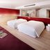 Hoshino Resorts Risonare Yatsugatake room with two beds, sofa seating, and mountain mural in Hokuto