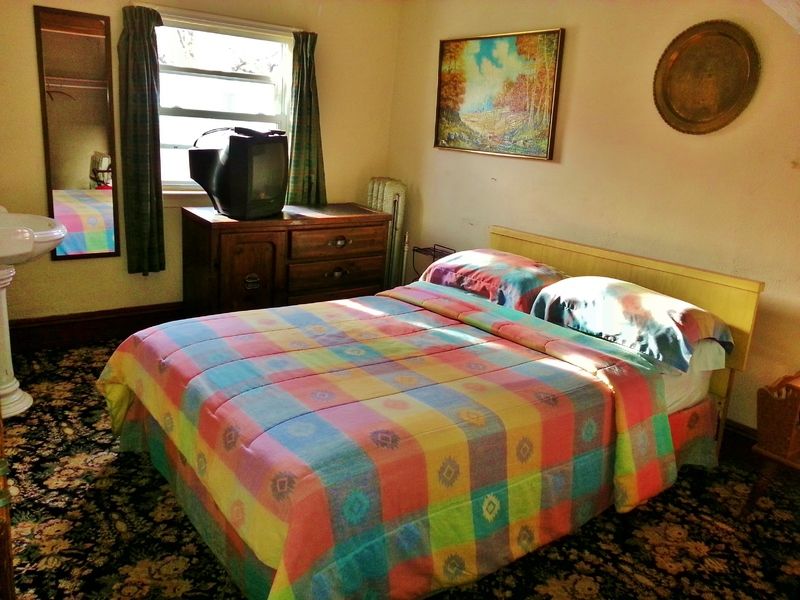 Harbor House Bed and Breakfast in Staten Island guest room with colorful bedspread, window and dresser