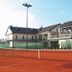 Kortowo in Poznan with clay tennis courts and a modern building beside the court