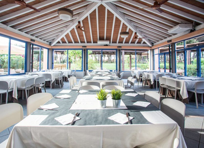 Garden Toscana Resort in San Vincenzo dining room with set tables and large windows overlooking greenery